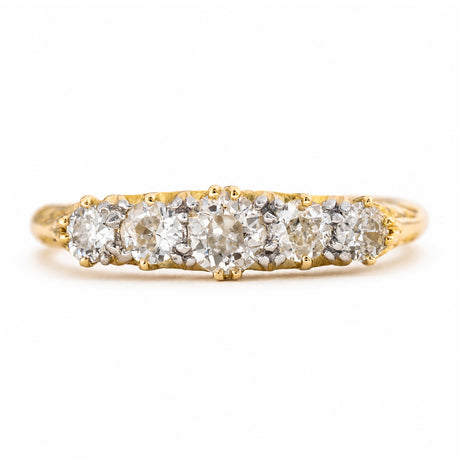 An Antique Victorian, yellow gold diamond ring featuring five diamonds set in a row, photographed on a clean white background.