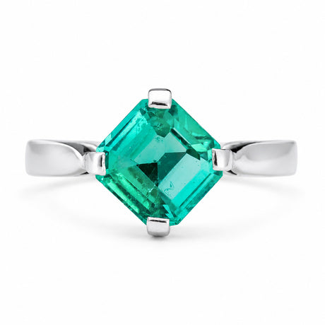A white gold vintage, 1990s emerald solitaire engagement ring. The large, square-cut emerald is set in a four-prong setting, shown against a plain white background.