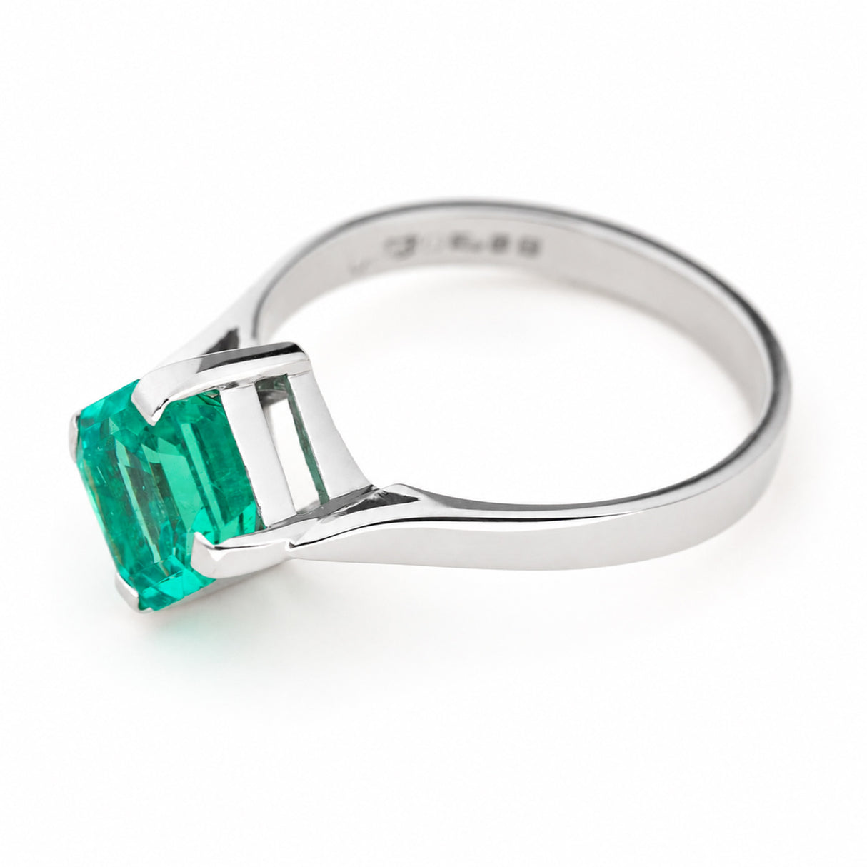 Side profile of a Vintage, 1990s emerald solitaire engagement ring in white gold, show on a clean white background. 