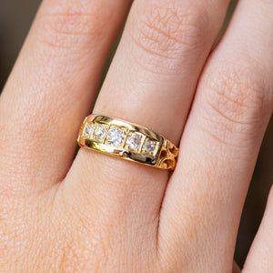 A yellow gold Antique, Victorian diamond five-stone engagement ring with carved shoulders worn of the finger and shown very close up.