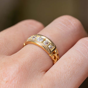 A close-up picture of an Antique, Victorian gypsy style diamond five-stone engagement ring in yellow gold worn on a person's finger and showcased from a low angle to display the profile of the ring.