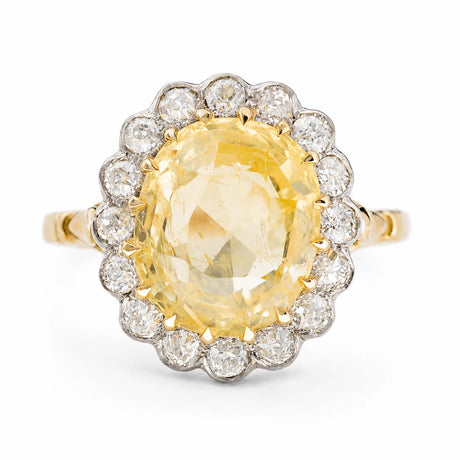 Vintage, 1950s yellow sapphire and diamond cluster engagement ring against a white background