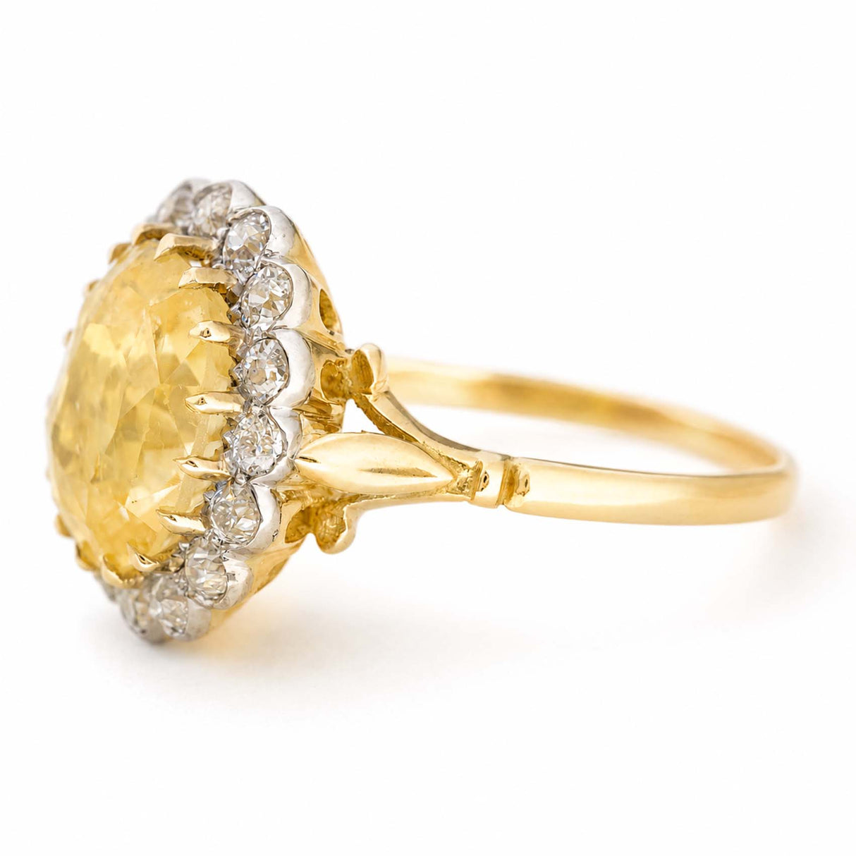 Vintage, 1950s yellow sapphire and diamond cluster engagement ring at an angle showing the split shoulders against a white background