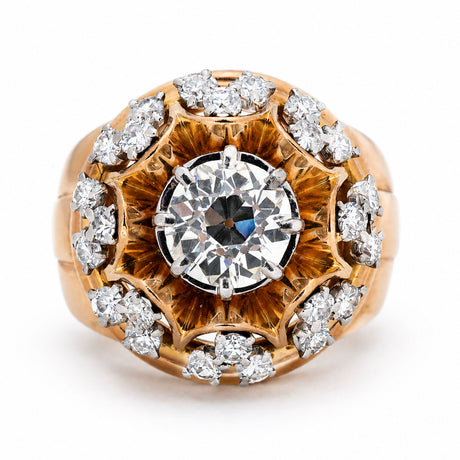 A Vintage, 1960s French old cut diamond cocktail ring featuring a central diamond surrounded by a halo of smaller diamonds set in intricate yellow gold work, shown on a plain white background.