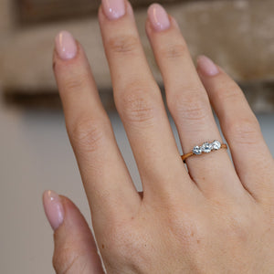 Antique three-stone diamond engagement ring worn on a hand, showcasing its elegant proportions and timeless Edwardian design.