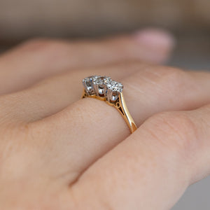 Side-angle view of the Edwardian three-stone ring worn on a hand, highlighting the elevated platinum settings and yellow gold band.