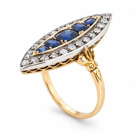 A sculptural three-quarter view reveals the elongated sapphire arrangement, diamond-set silver surround and engraved yellow gold shoulders.