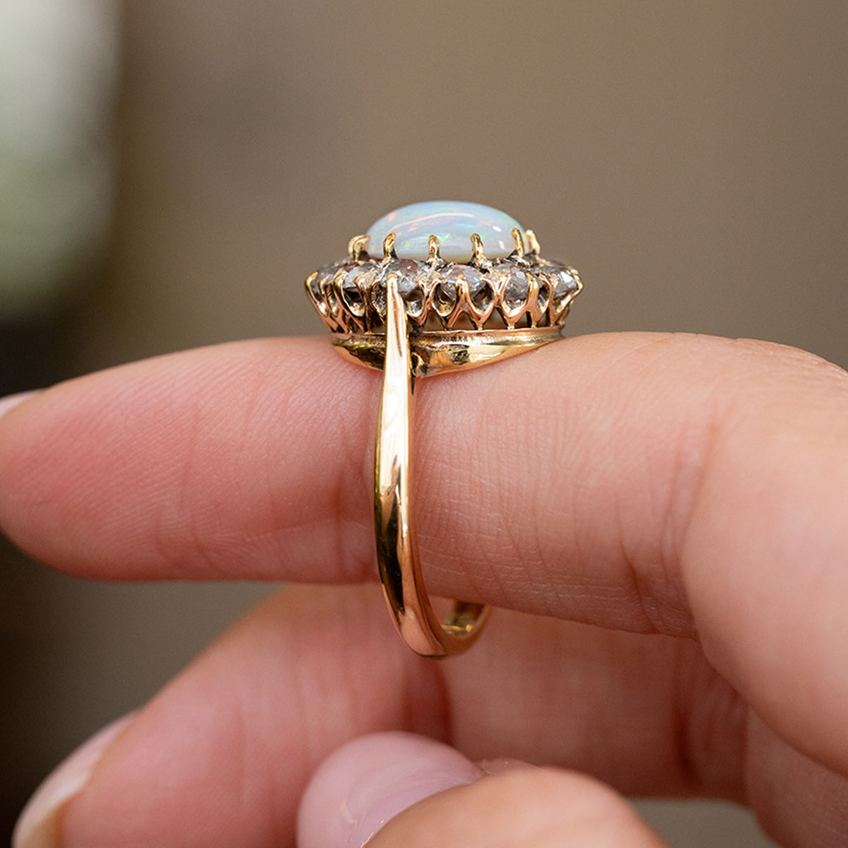 Profile of the Edwardian cluster ring displaying the elevated opal setting, open gallery and slender yellow gold shank.