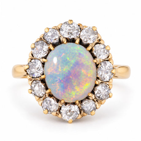 Antique Edwardian opal cabochon and diamond cluster ring in yellow gold, centred with a colourful oval opal surrounded by old-cut diamonds.