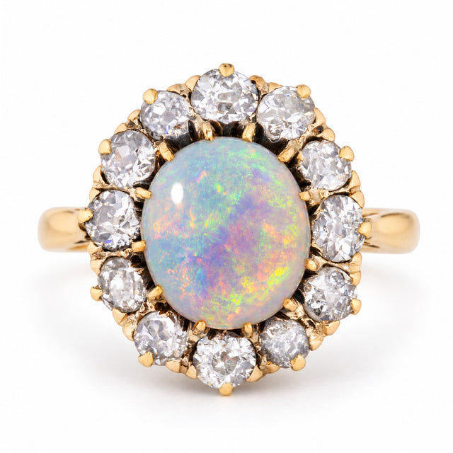 Antique Edwardian opal cabochon and diamond cluster ring in yellow gold, centred with a colourful oval opal surrounded by old-cut diamonds.