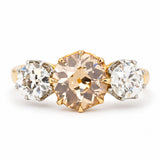 An Antique, Edwardian brown diamond three-stone engagement ring in platinum against a white background