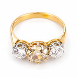 A yellow gold Antique, Edwardian brown diamond three-stone engagement ring shown against a white background from an elevated angle to show the setting style of the ring. 