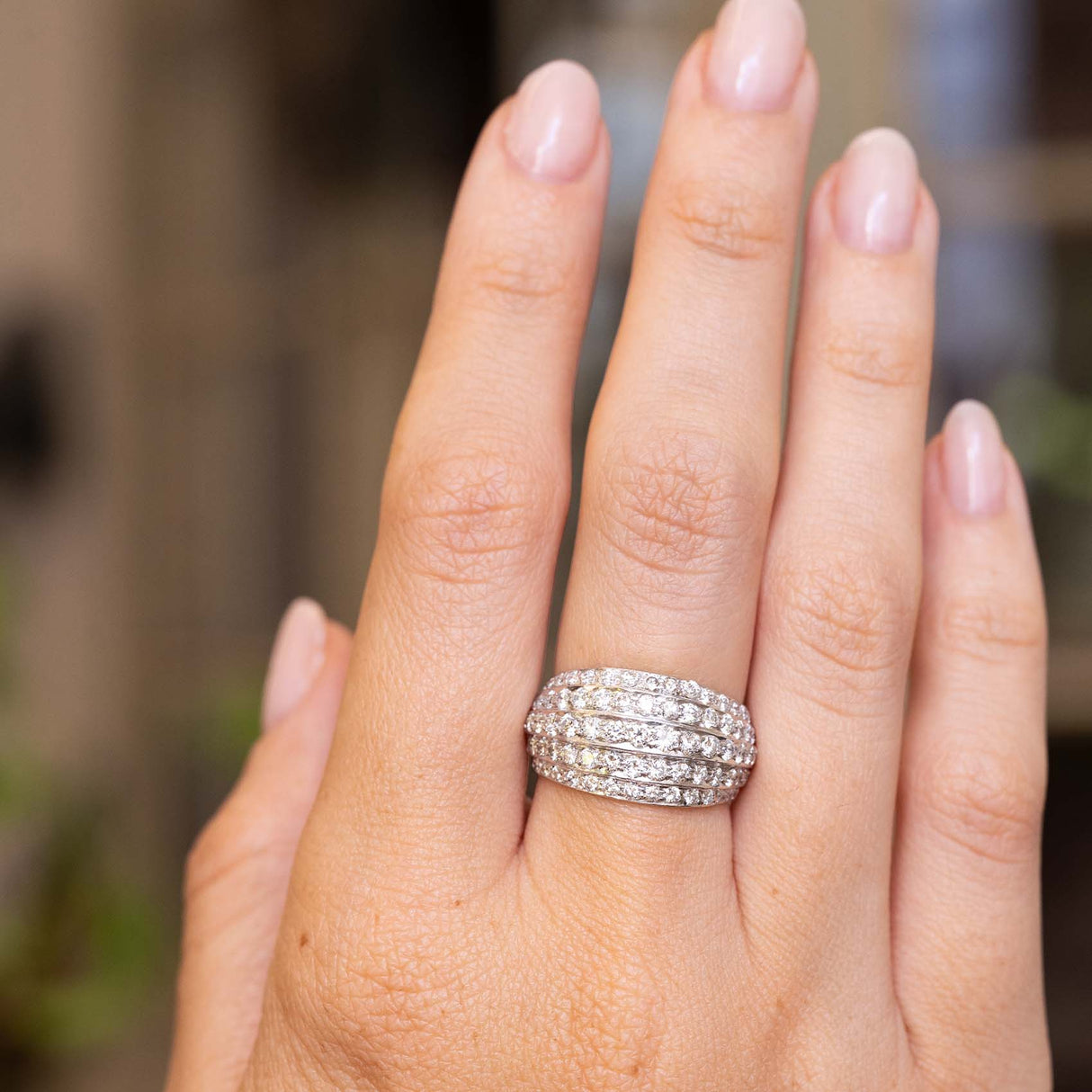 A close-up of a hand wearing a A Vintage, 1950s diamond bombe cocktail ring in white gold 