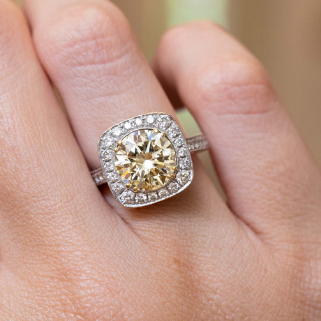 A close-up of a hand wearing a Vintage, 1990s yellow tinted diamond cluster engagement ring 