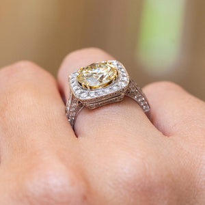 A close-up of a hand wearing a Vintage, 1990s yellow tinted diamond cluster engagement ring in white gold
