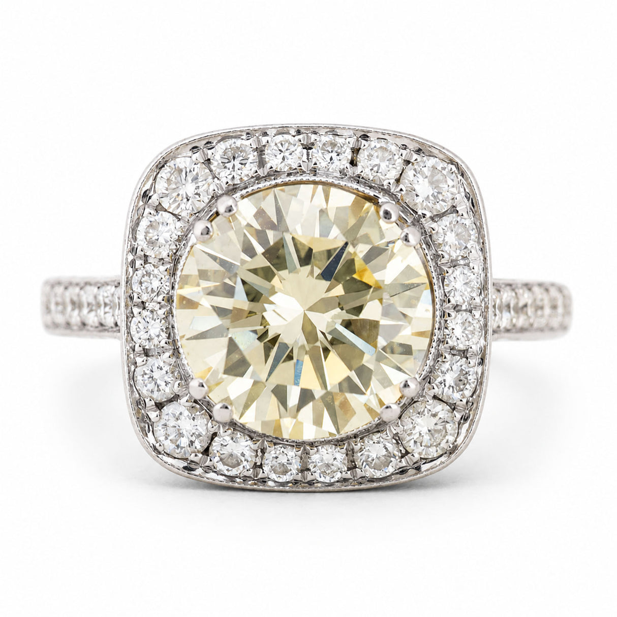 Vintage, 1990s yellow tinted diamond cluster engagement ring in white gold against a plain white background