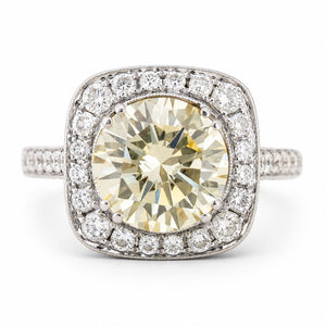 Vintage, 1990s yellow tinted diamond cluster engagement ring in white gold against a plain white background