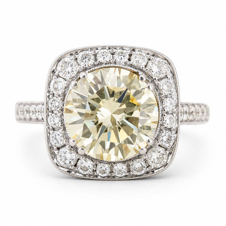 Vintage, 1990s yellow tinted diamond cluster engagement ring in white gold against a plain white background
