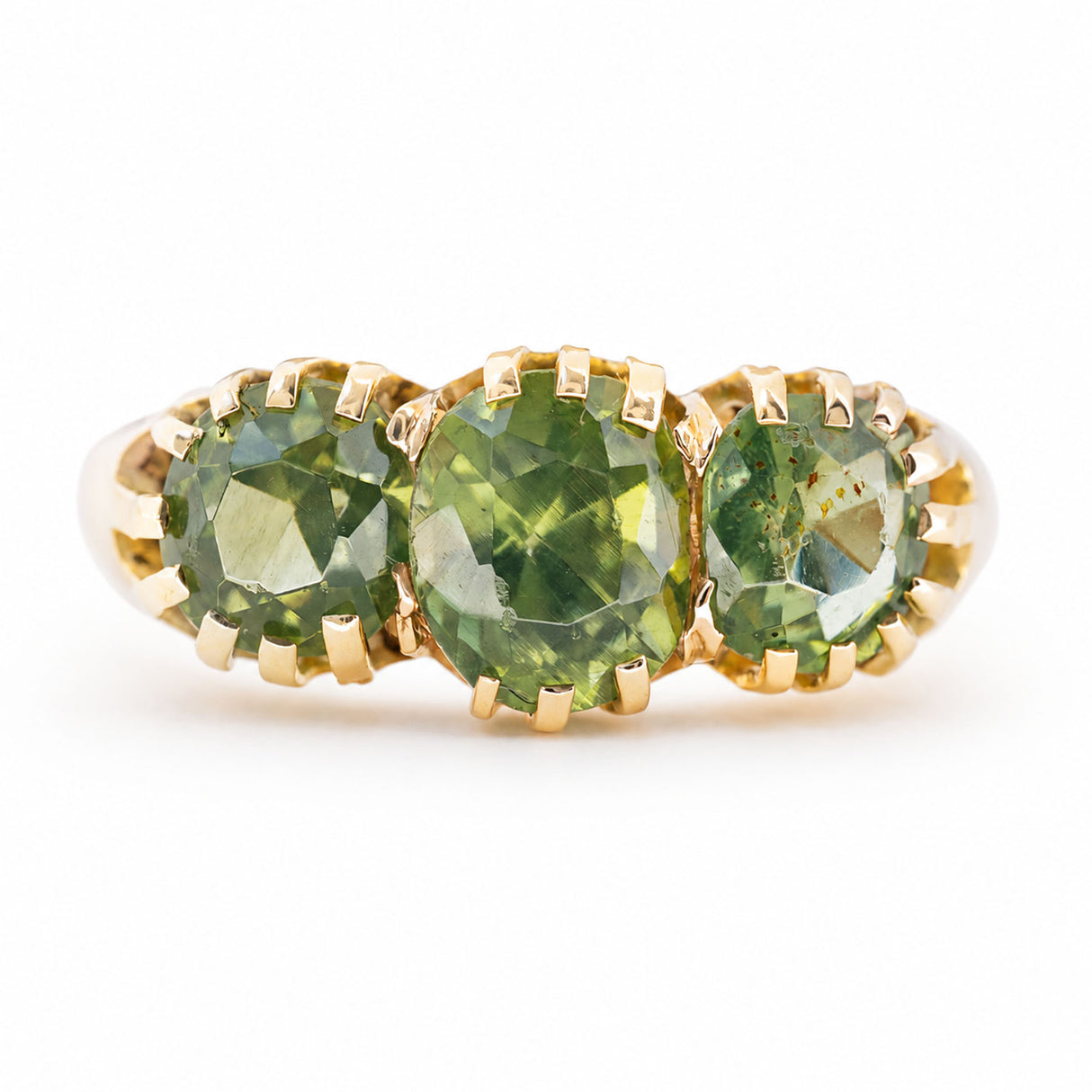 A gold green zircon three-stone ring shown against a plain white background.