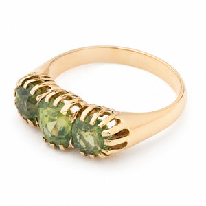 A gold metal green zircon three-stone ring shown from above at an angle against a white background.