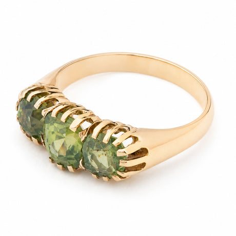 A gold metal green zircon three-stone ring shown from above at an angle against a white background.