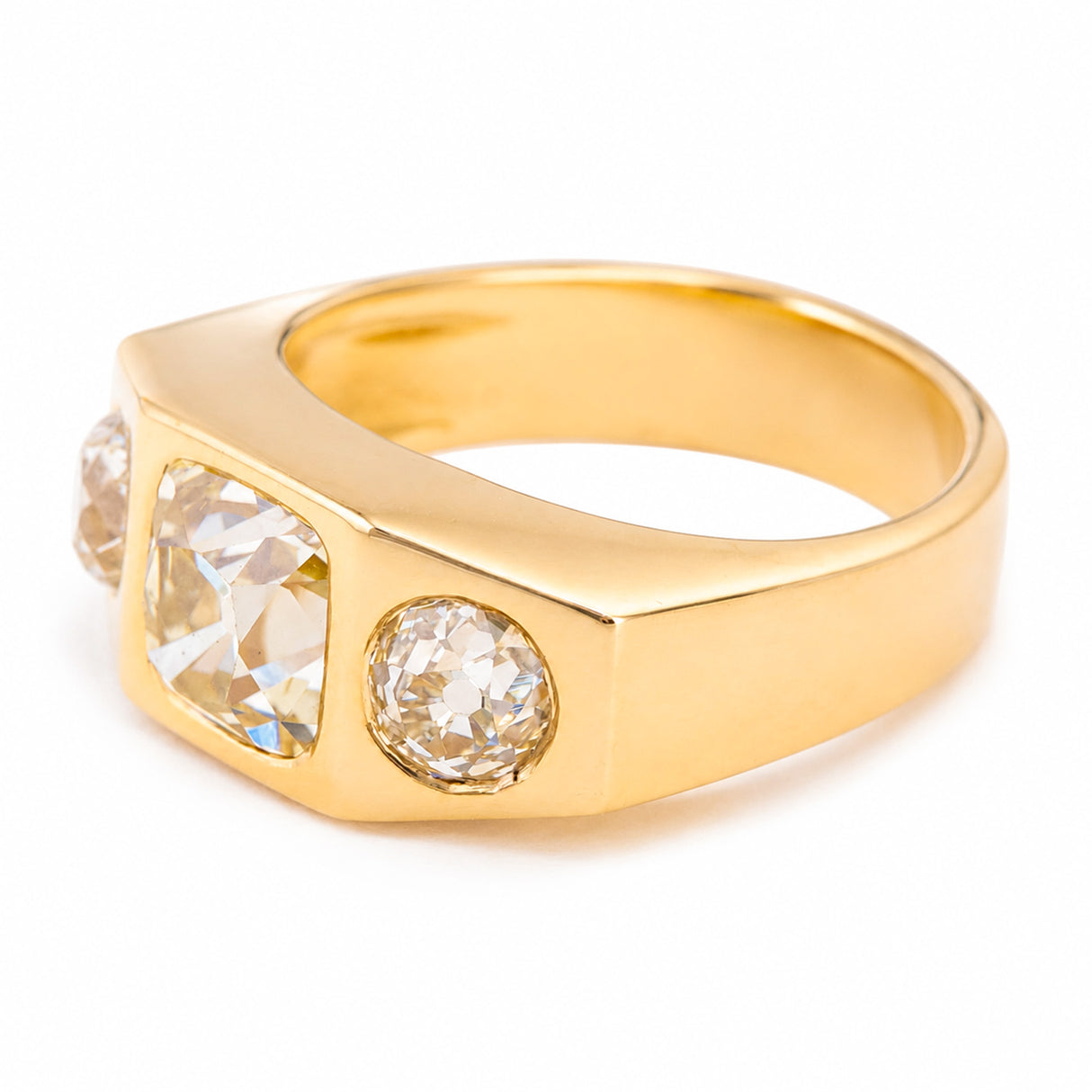 A Vintage, 1970s Peruzzi cut diamond trilogy gypsy ring yellow gold detail against white background.