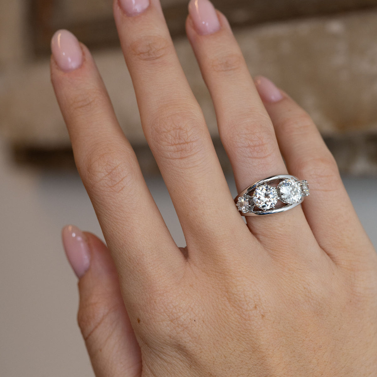 1950s diamond engagement ring worn on a hand, showcasing its elegant proportions and unique four-stone arrangement.
