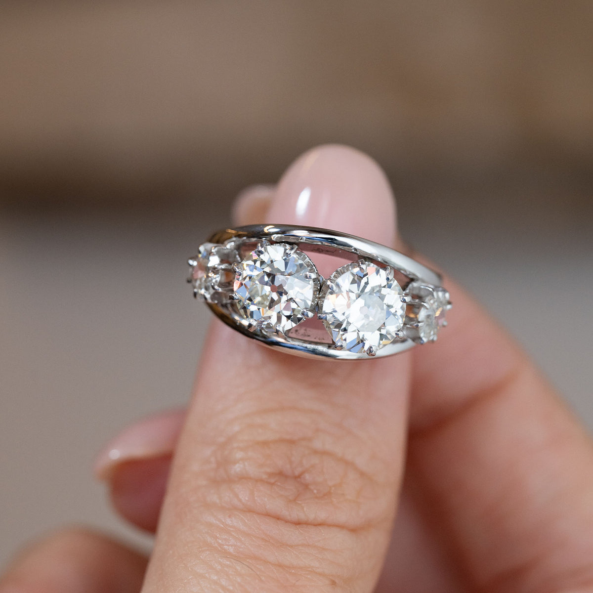 Hand-held close-up of the four old-cut diamonds arranged within a distinctive openwork white metal setting.