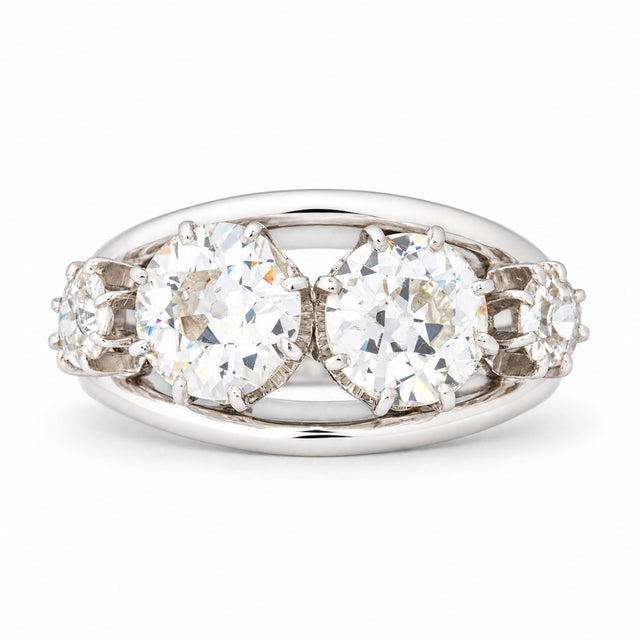 Vintage 1950s old-cut diamond four-stone engagement ring in white gold and platinum, featuring two larger central diamonds and smaller diamond shoulders.
