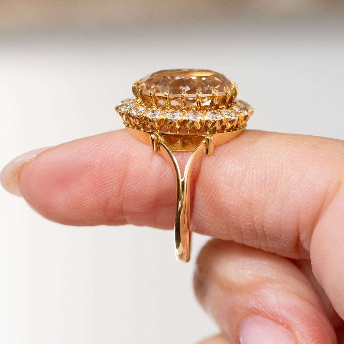 Profile detail of the vintage yellow gold ring, revealing its high-set oval topaz, decorative diamond gallery and slender band.