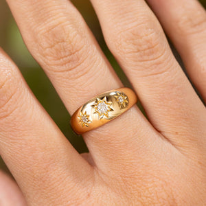 An up close image of an antique Edwardian diamond three stone gypsy ring style with polished yellow gold and three old cut diamonds and engraved star settings