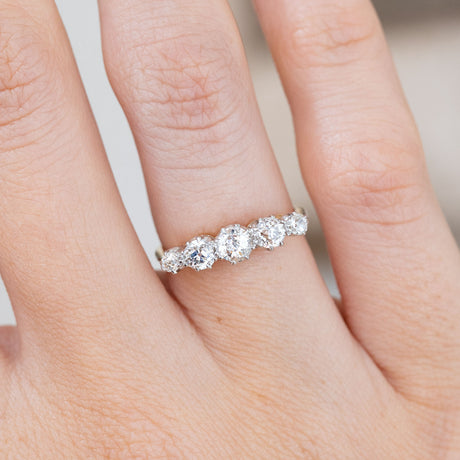 Detailed hand close-up showing the larger central diamond tapering into smaller old-cut stones on either side.
