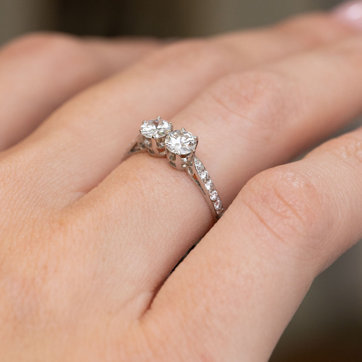 Side-angled view of the Art Deco two-diamond ring being worn, highlighting the elevated claw settings and diamond shoulders.