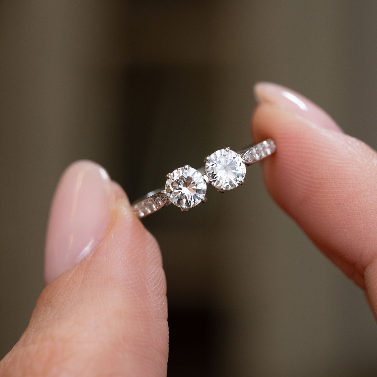 Handheld close-up of the platinum toi et moi ring, featuring two bright transition-cut diamonds in a romantic paired design.