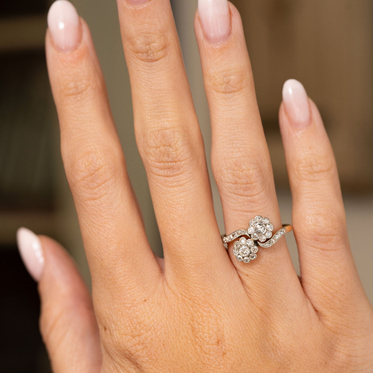 A hand wearing an Antique, Edwardian diamond toi et moi engagement ring in yellow gold.