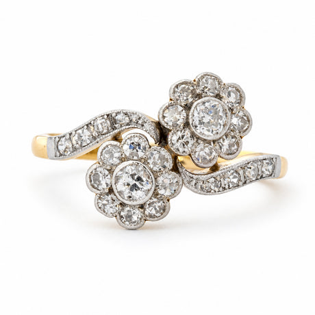 Antique, Edwardian diamond toi et moi crossover engagement ring in yellow gold against a plain white background