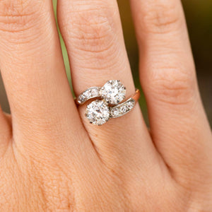 A close-up image of a hand wearing a yellow gold Antique, Edwardian diamond toi et moi engagement ring