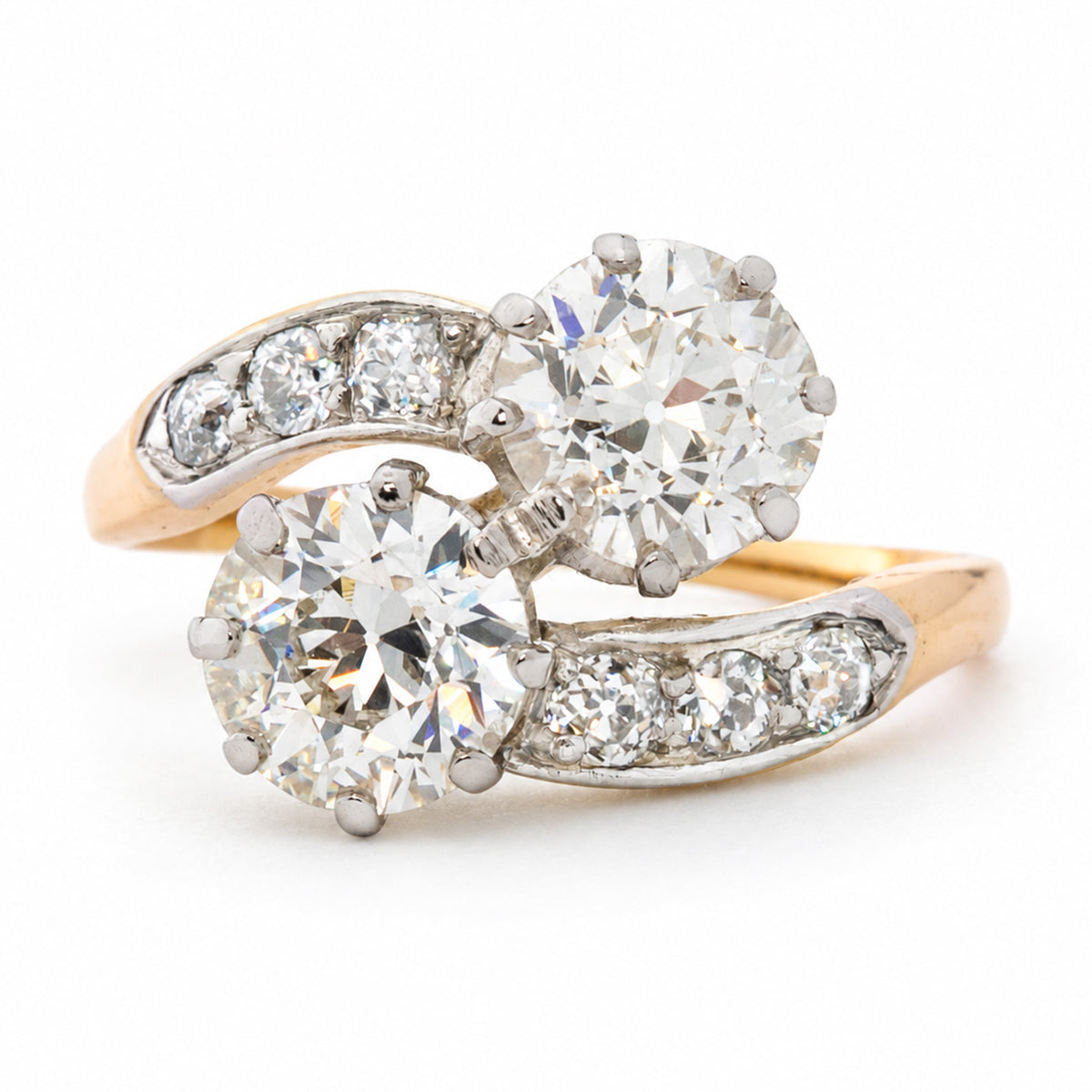An antique Edwardian old cut diamond two stone engagement ring in yellow gold on a white background