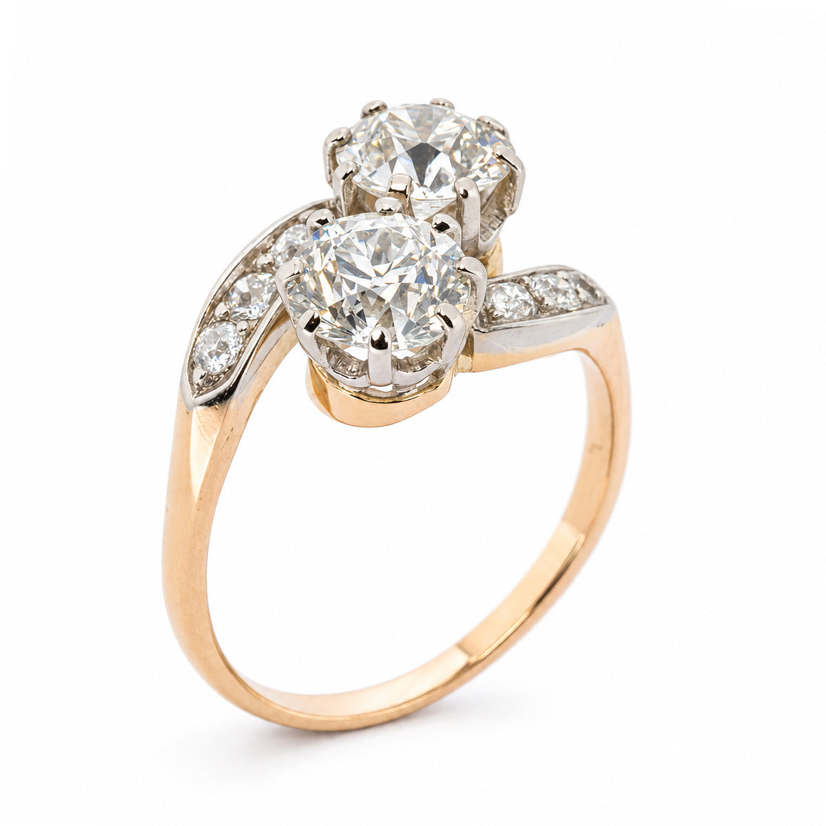An Edwardian Toi et Moi two stone crossover engagement ring in yellow gold at a vertical position against a plain white background