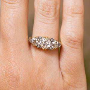Close-up of an antique engagement ring worn, featuring three claw-set old-cut diamonds interspersed with tiny rose-cut diamonds.