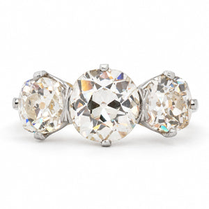 Antique, Edwardian old-cut diamond three-stone engagement ring with platinum settings and a gold band against a plain white background.