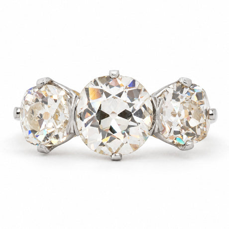 Antique, Edwardian old-cut diamond three-stone engagement ring with platinum settings and a gold band against a plain white background.