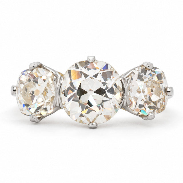 Antique, Edwardian old-cut diamond three-stone engagement ring with platinum settings and a gold band against a plain white background.
