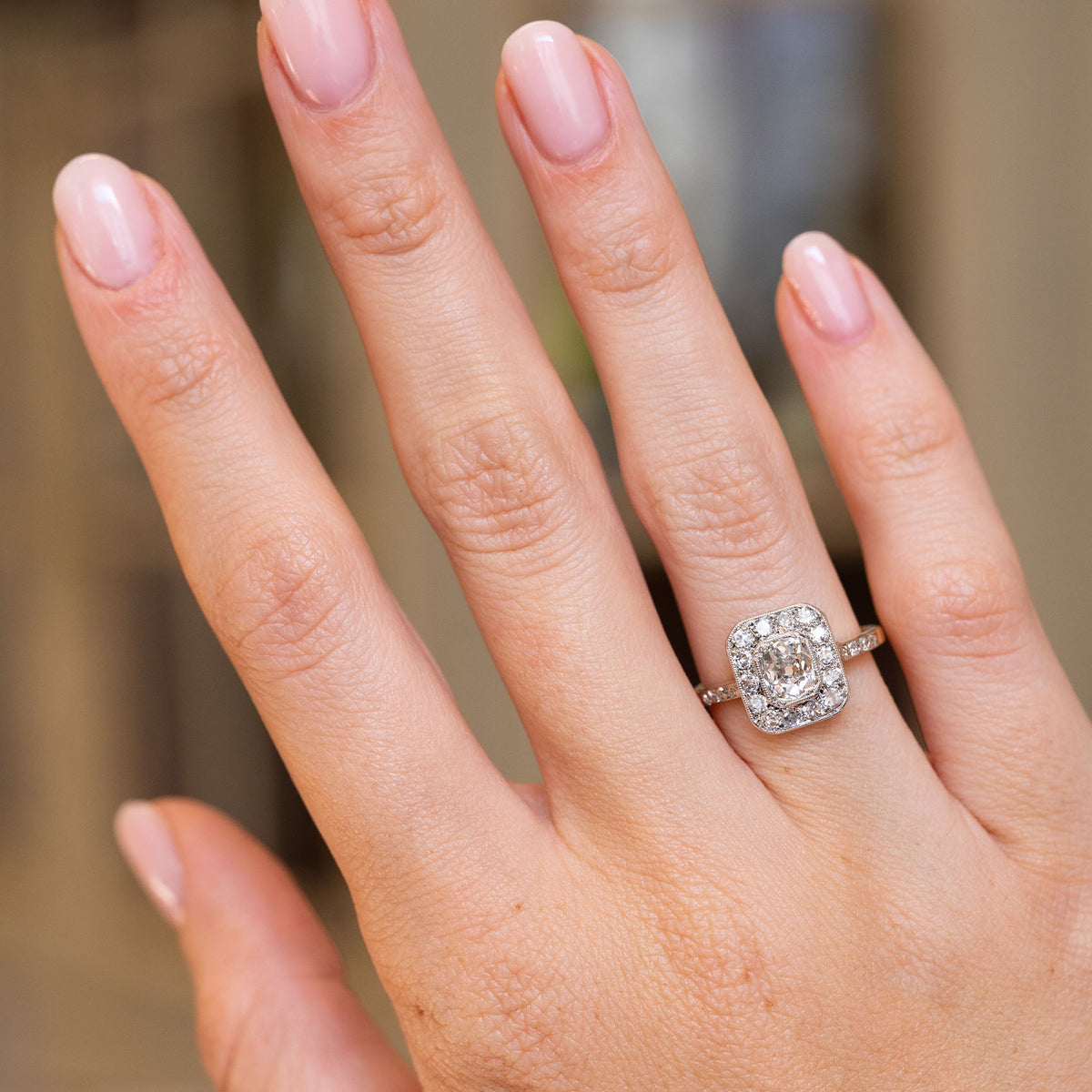 Antique Edwardian diamond cluster ring worn on the hand, showcasing its old-mine diamonds and contrasting yellow gold band.