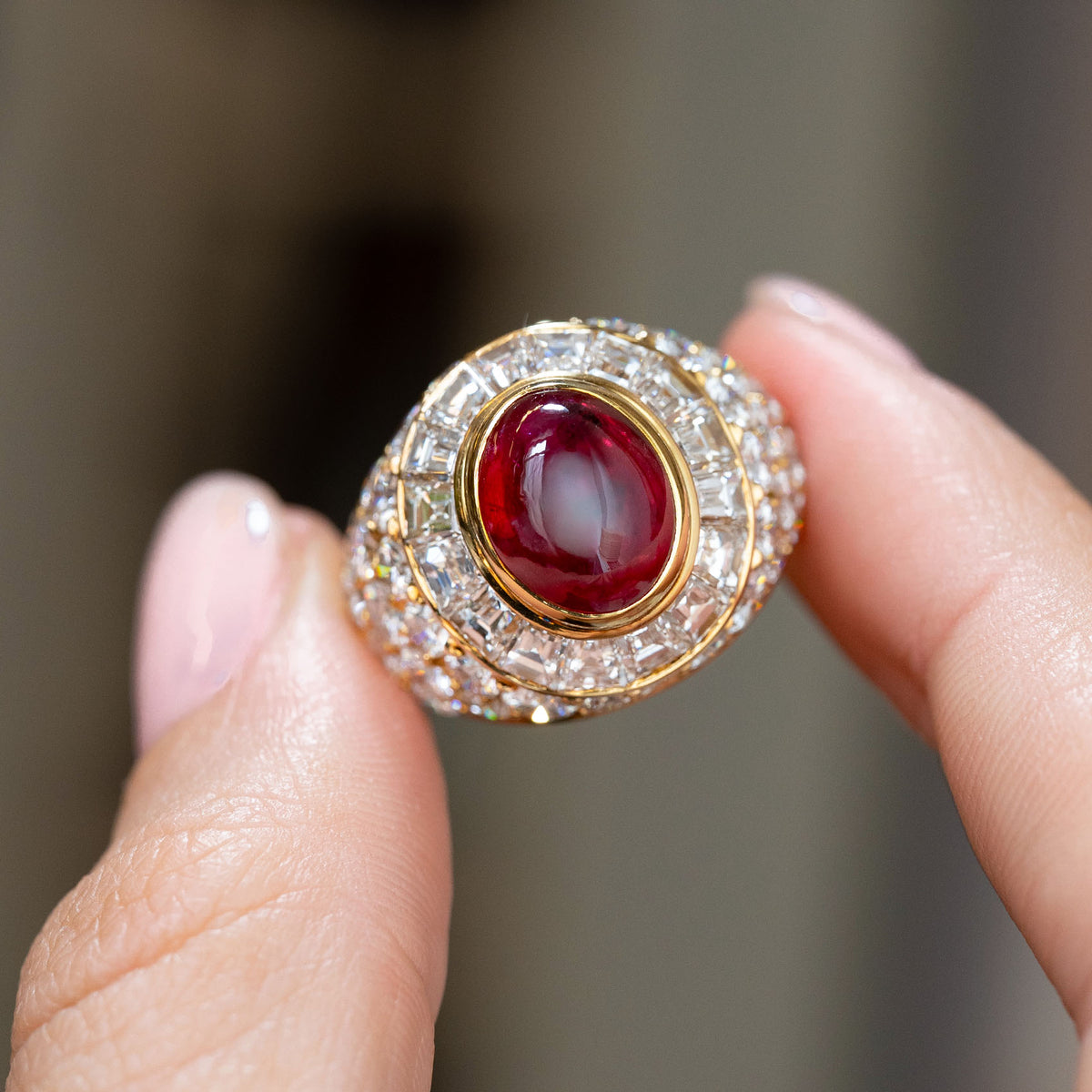 Vintage Asprey ruby cocktail ring held between the fingers, offering a detailed look at its geometric diamond arrangement.