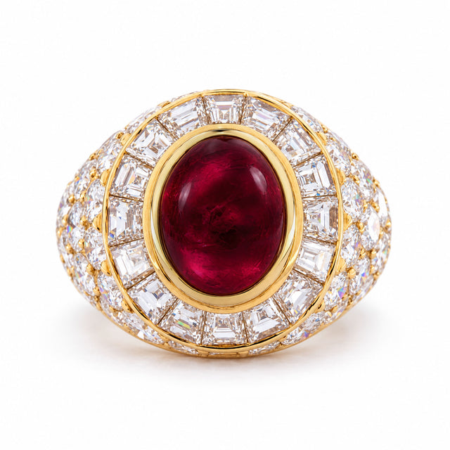 Vintage Asprey cocktail ring in yellow gold, centred with an oval cabochon ruby and surrounded by tapered step-cut and round brilliant diamonds.