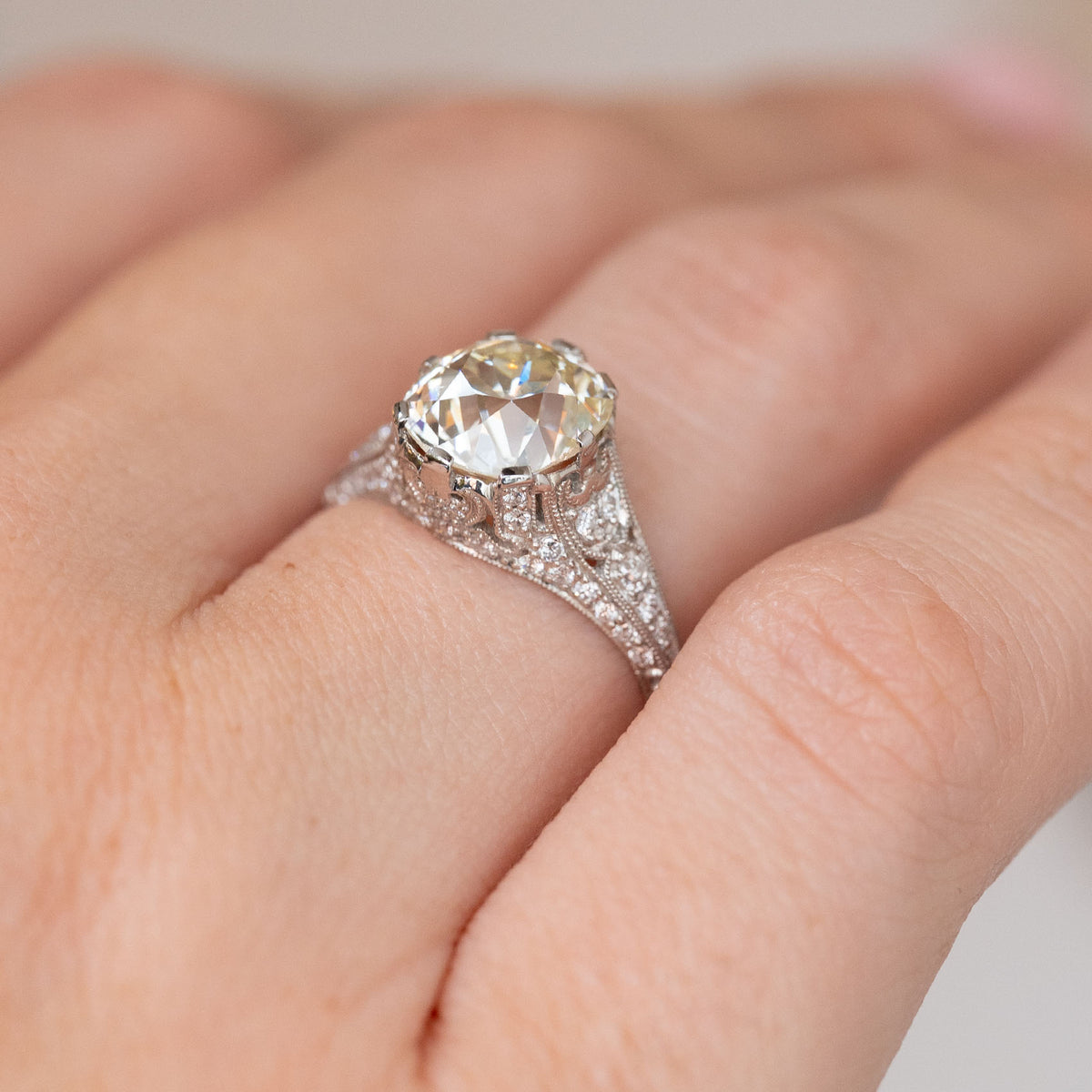 Side angle of the antique engagement ring, revealing the elevated centre stone and diamond-set filigree shoulders.