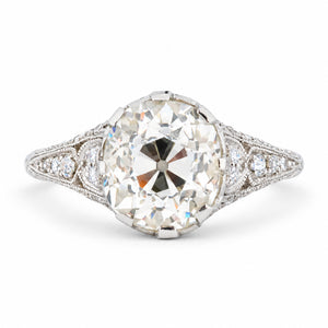 Antique Edwardian old-mine cut diamond solitaire engagement ring with diamond-set shoulders and delicate milgrain detailing.