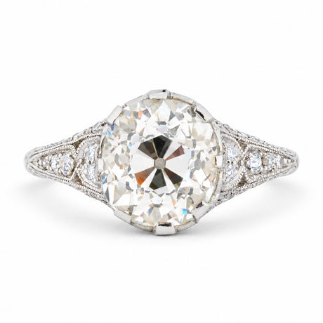 Antique Edwardian old-mine cut diamond solitaire engagement ring with diamond-set shoulders and delicate milgrain detailing.