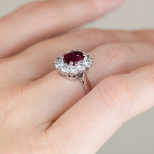 Angled view of the 1960s ruby and diamond engagement ring worn on a finger, displaying the raised cluster head and delicate white gold shoulders.
